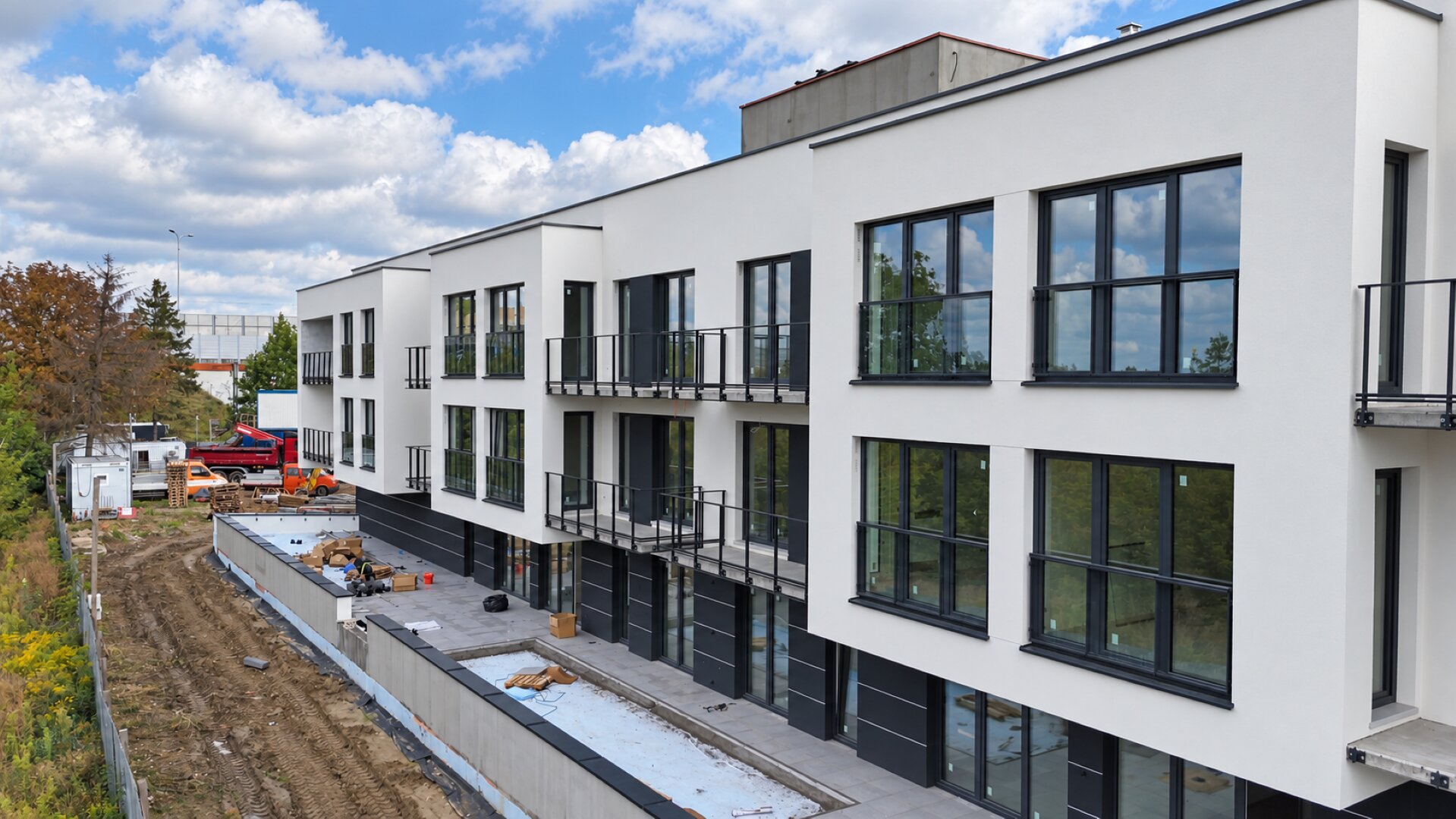 Miniatura: Budynek A — zbliżenie na białą elewację, okna i balustrady
